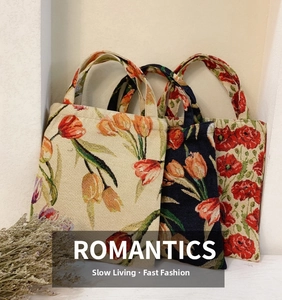 Three jacquard tote bags with tulip patterns stacked against a minimalist wall