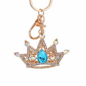 Golden crown keychain with sparkling blue crystal and rhinestones on white background