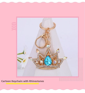 Close-up of golden crown keychain with blue drop gem and sparkling rhinestones