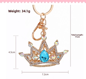 Detail view of gold crown keychain with sparkling rhinestones and blue teardrop gem