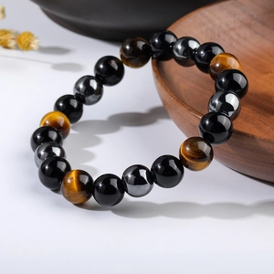 Macro shot of tiger eye and black obsidian bead bracelet on a wooden display