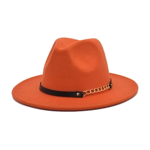 Detail of orange wool fedora featuring a black leather band and gold chain accent