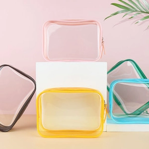 Various colorful PVC clear toiletry bags with zippers arranged on a display stand