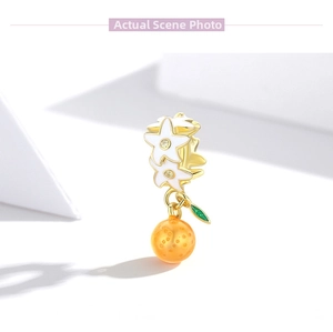 Macro detail of S925 silver orange charm with white enamel stars and golden finish