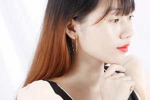Close-up of oversized golden hoop earring on model showing real scale and metallic shine
