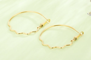 Detailed close-up of golden large hoop earrings featuring unique wavy bottom curve design
