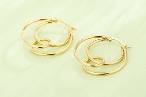 Macro detail of gold-plated geometric interlocking triple hoop earrings with polished finish