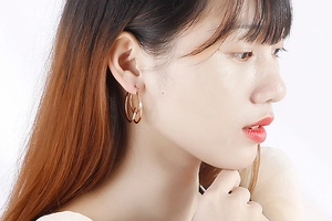 Macro detail of geometric knotted double circle earrings in rose gold on model