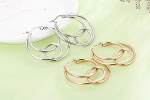 Detail of interlocking silver and gold geometric hoop earrings on a textured background