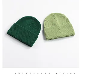 Detail of dark green and light lime knit beanies with thick ribbed texture and cuffs