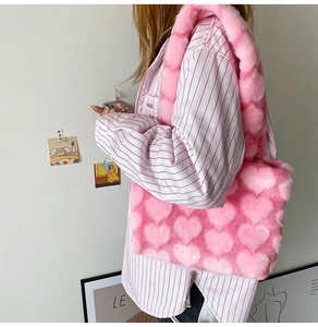 Detail view of pink heart plush tote bag worn by a model in a minimalist lifestyle setting
