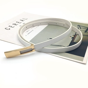 Close-up of white leather thin belt with gold rectangular buckle on minimalist magazine