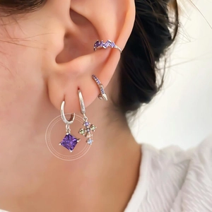 Close-up of S925 silver hoop earrings with purple zircon pendants and cross charm on ear