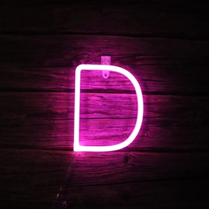 Pink LED neon letter D light mounted on dark wood wall for decorative indoor lighting