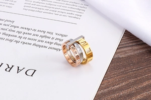 Detailed view of tricolor interlocking stainless steel rings with Roman numerals and crystals