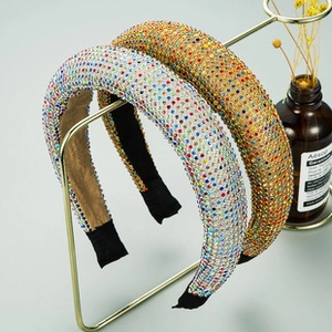 Close-up of luxury knotted headbands with multicolored rhinestones on gold display stand