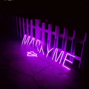 Macro detail of purple LED neon Marry Me sign with heart for romantic proposal decor