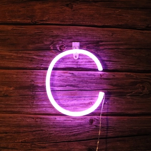 Detail of purple LED neon letter C light on a rustic wood wall for room decoration