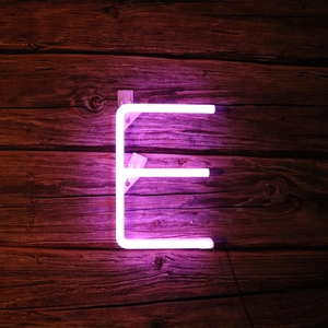 Detailed view of neon letter E sign emitting purple light on rustic dark wooden wall
