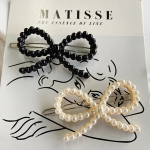 Detail of bow-shaped acetate hair clips with pearl beads on a minimalist card