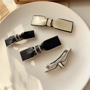 Detailed view of elegant bow hair clips with contrasting trim on a white ceramic plate