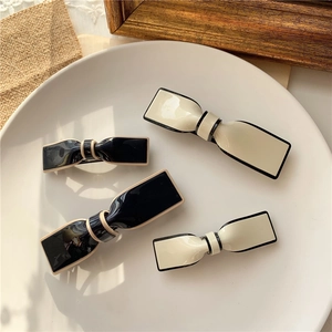 Detail of minimalist bow hair clips with contrasting edges in black and cream