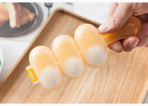 Manual translucent orange bear-shaped rice ball maker being held over a wooden tray