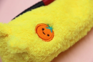 Close-up of cute yellow plush pencil case with soft lamb wool and fruit embroidery