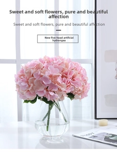 Close-up of five-head pink hydrangea silk flowers in a clear glass vase by the window