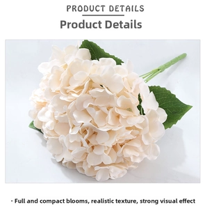 Close-up of cream white artificial hydrangea petals and green leaves on marble