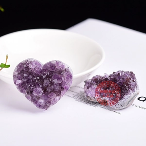 Macro shot of heart-shaped natural amethyst geode clusters on a white display setting