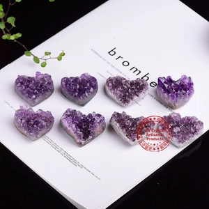 A set of eight heart-shaped natural amethyst clusters displayed with green plants