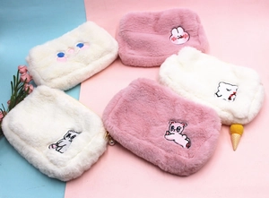 Gros plan de trousses à maquillage en peluche avec broderie animale et breloque perle