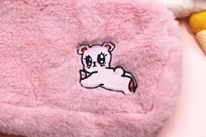 Gros plan d'une trousse à maquillage en peluche rose avec broderie d'ours détaillée