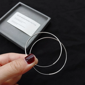 Detailed view of large S925 sterling silver hoop earrings held to show size and texture