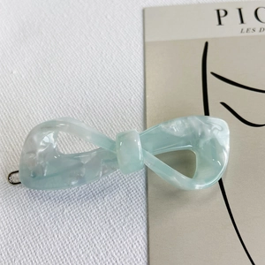 Detail of blue marble texture acetate bow hair clip on elegant white fabric background