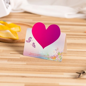 3D pink heart greeting card with floral patterns and butterflies on a wooden desk