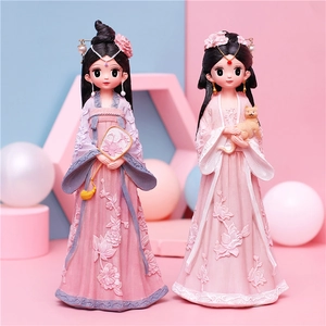 Detail of two cute resin figures in Hanfu holding a traditional fan and a small cat
