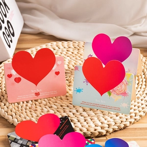3D heart pop-up greeting cards in red and pink on a textured woven mat setting