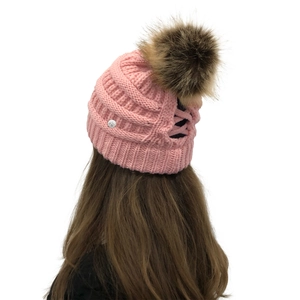 Detail view of pink knit beanie with high ponytail hole and large faux fur pompom