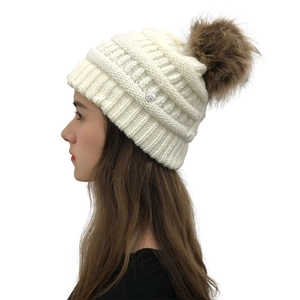 Detail of cream knit beanie featuring cross pattern texture and round flower metal button