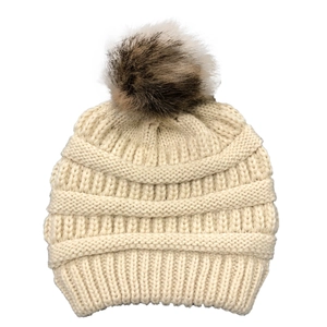 Detailed knit texture of a beige winter beanie with a fluffy brown faux fur pom pom