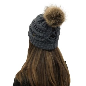 Detailed knit texture of dark grey beanie with a fluffy brown faux fur pom pom decoration