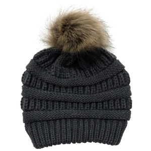 Detailed knit texture and brown faux fur pom-pom on a dark gray winter beanie hat