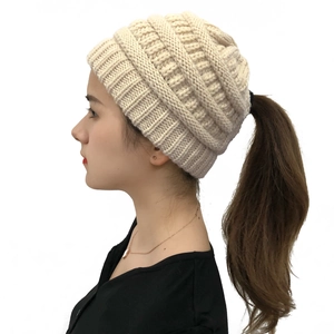 Detail of beige chunky knit ponytail beanie showing the rear opening for hair
