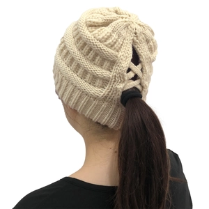 Detail of beige knit beanie showing the ponytail opening on the textured back