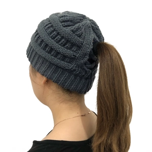Detail of dark grey thick knit beanie featuring a functional ponytail hole design