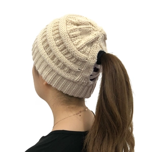 Detail of the ponytail hole design and knit texture on the beige winter beanie cap