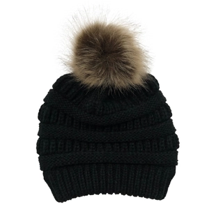 Detail of black knit beanie featuring a premium faux fur pompom and ribbed texture
