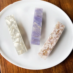 Three acetate leopard hair clips with pearlescent and floral patterns on ceramic plate